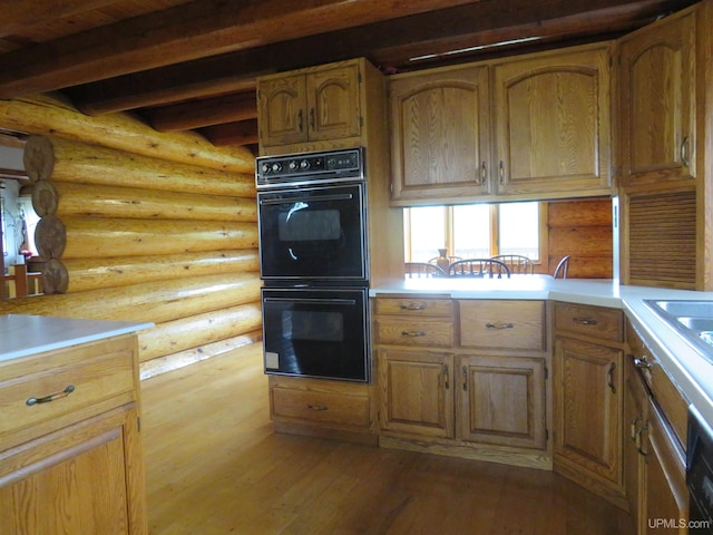 kitchen featuring beamed ceiling, double oven, log walls, and light hardwood / wood-style flooring