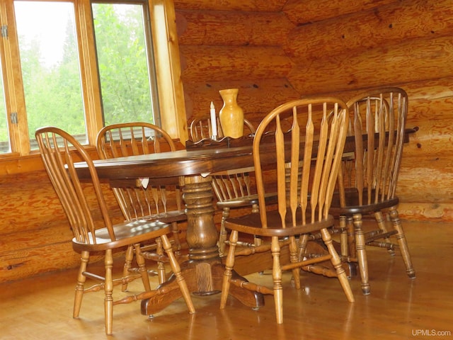 dining area featuring a healthy amount of sunlight, light hardwood / wood-style flooring, and rustic walls