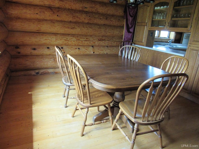 dining space with light hardwood / wood-style flooring and log walls