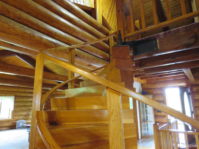 staircase with log walls and beam ceiling