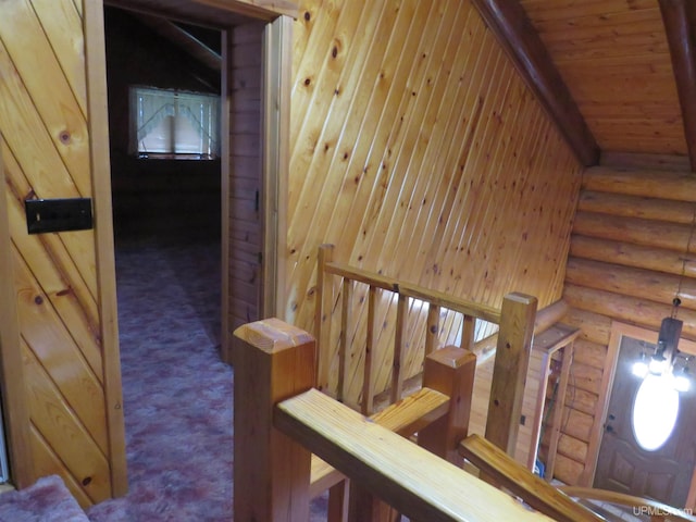 stairway featuring vaulted ceiling, carpet, and rustic walls