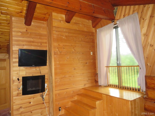 interior space with wood walls, a fireplace, and beam ceiling