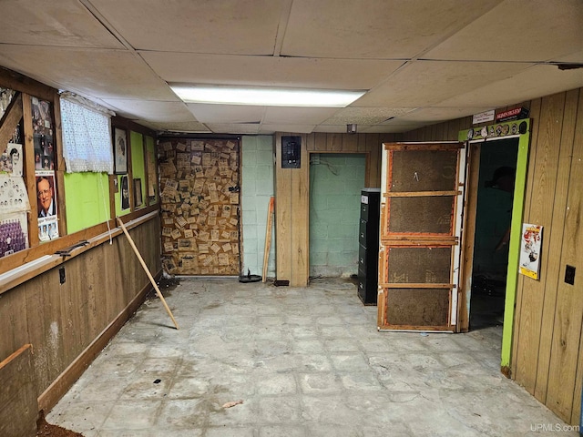 basement with wood walls and a paneled ceiling