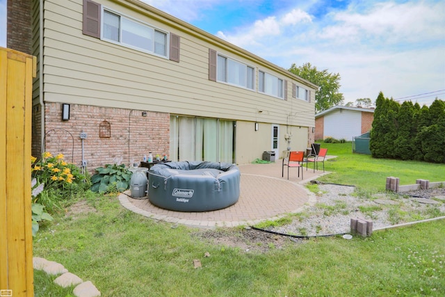rear view of property with a yard, a patio, and brick siding
