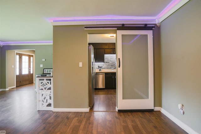 hallway with dark wood-style flooring, baseboards, and a barn door