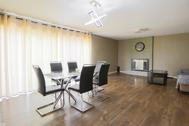 dining area with brick wall, a fireplace, and hardwood / wood-style floors