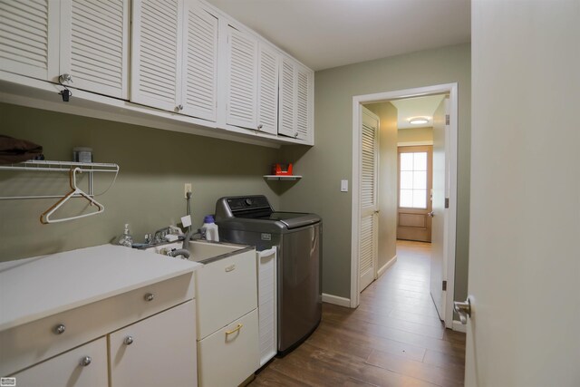 clothes washing area with washer and clothes dryer, dark hardwood / wood-style floors, and cabinets