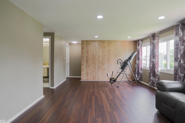 exercise area featuring dark hardwood / wood-style flooring and wooden walls