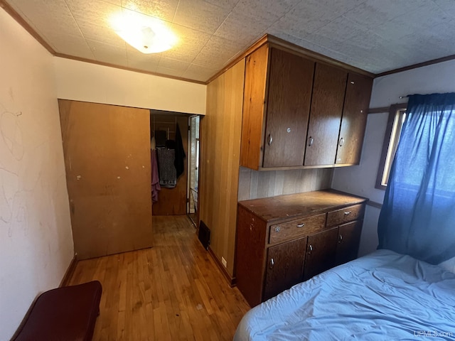 bedroom with crown molding and light hardwood / wood-style floors