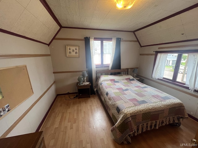 bedroom featuring crown molding, lofted ceiling, and light wood-type flooring