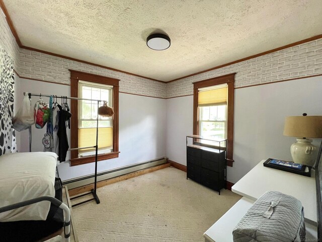 bedroom with multiple windows, brick wall, a textured ceiling, and a baseboard heating unit