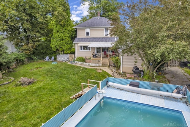 rear view of house featuring a swimming pool side deck and a lawn