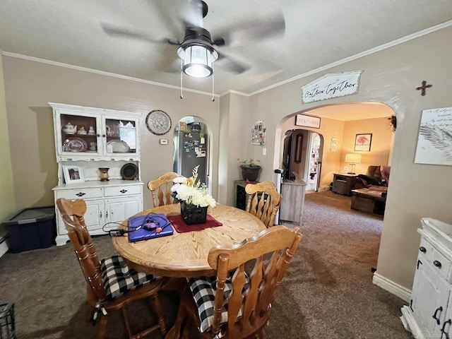 dining space featuring ceiling fan, crown molding, and dark carpet