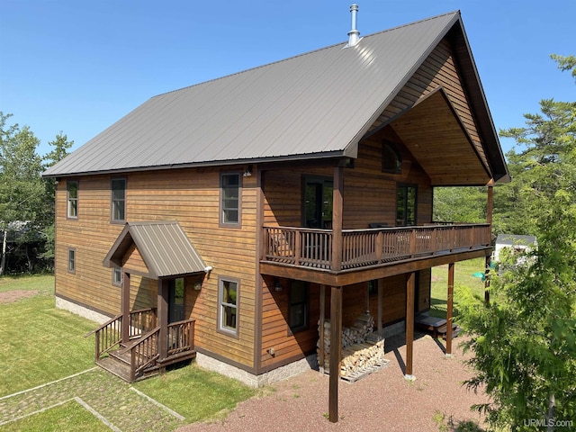 back of house featuring a garage, metal roof, and a lawn