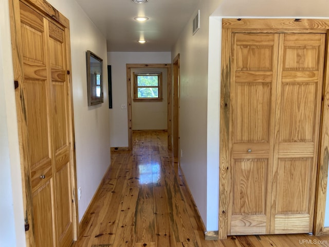 hallway with baseboards, visible vents, and hardwood / wood-style floors