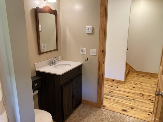 bathroom with toilet, tile patterned floors, baseboards, and vanity