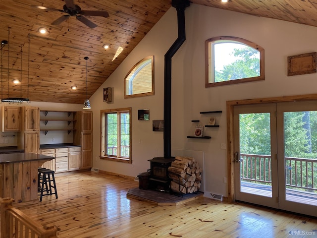 unfurnished living room featuring light wood-style flooring, a wood stove, wooden ceiling, and visible vents