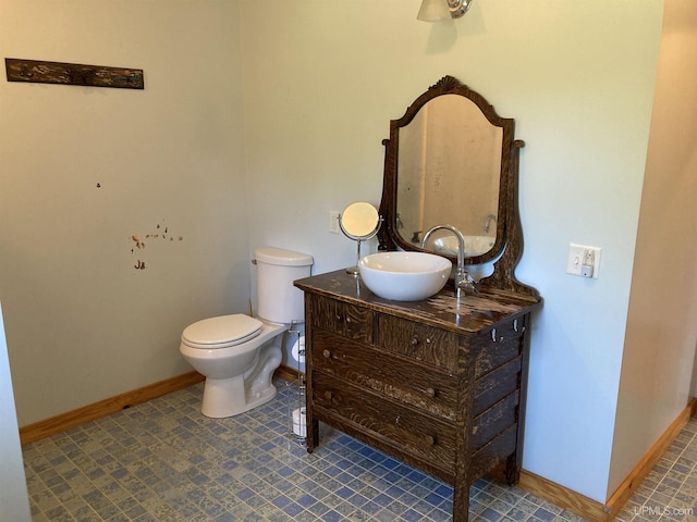 half bath with toilet, vanity, and baseboards