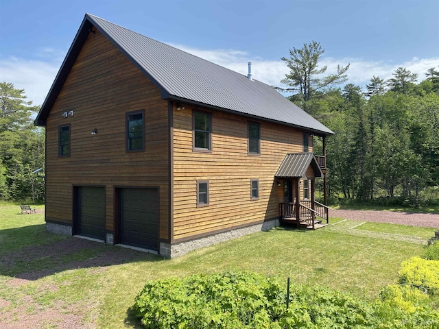 view of side of home with metal roof, driveway, a lawn, and a garage