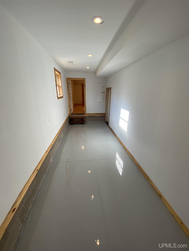 corridor with recessed lighting, finished concrete flooring, and baseboards