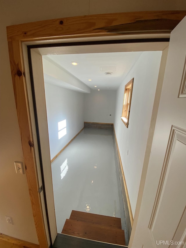 hallway with finished concrete flooring and baseboards