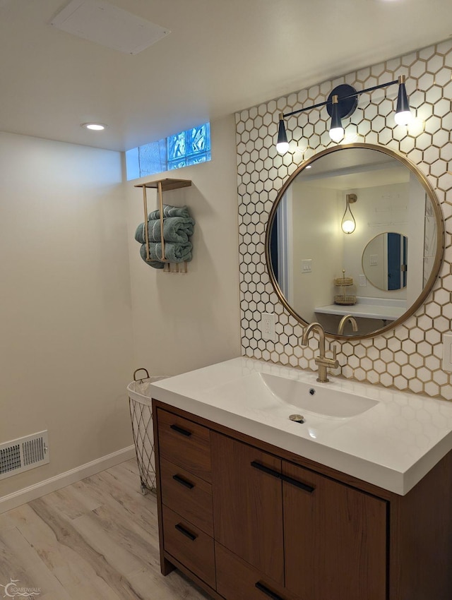 bathroom featuring hardwood / wood-style flooring, vanity, and decorative backsplash