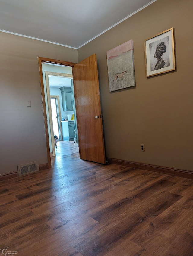 empty room featuring dark hardwood / wood-style flooring and crown molding