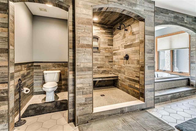 bathroom with independent shower and bath, tile walls, toilet, and tile patterned floors