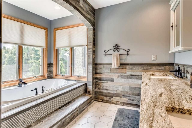 bathroom featuring a relaxing tiled tub, tile patterned floors, and vanity