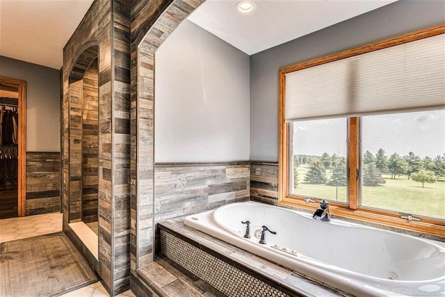 bathroom with tile patterned flooring, a walk in closet, and a garden tub