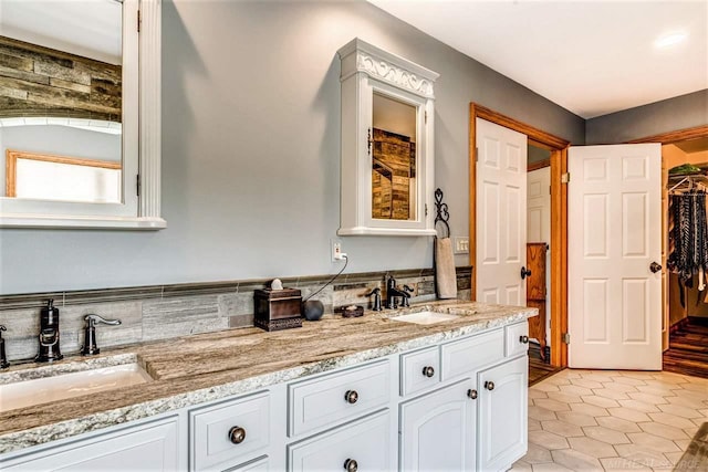 bathroom featuring a walk in closet, tile patterned floors, a sink, and double vanity