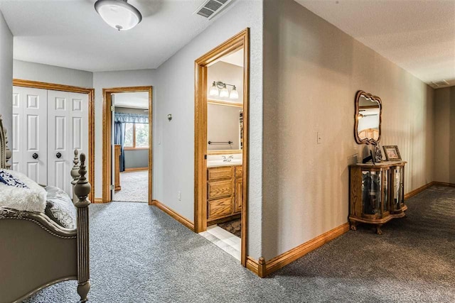 corridor featuring carpet floors, visible vents, and baseboards