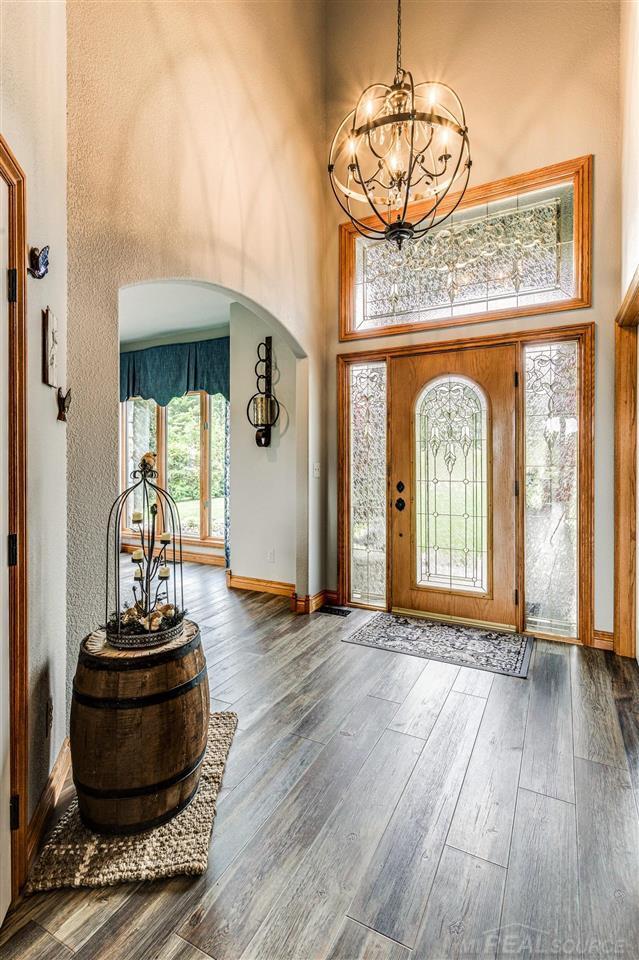 entrance foyer featuring an inviting chandelier, hardwood / wood-style floors, a wealth of natural light, and a high ceiling