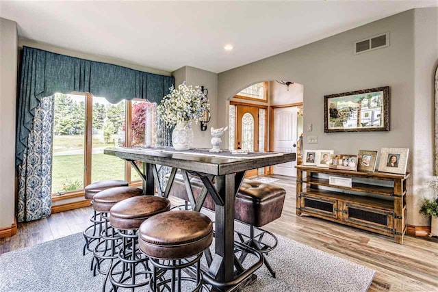 dining area with arched walkways, recessed lighting, visible vents, wood finished floors, and baseboards