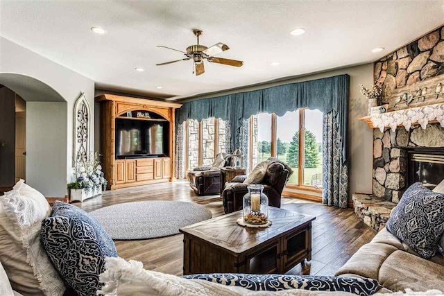 living room featuring wood-type flooring, a fireplace, and ceiling fan