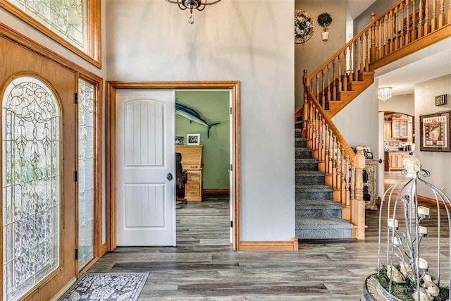 entrance foyer with a high ceiling, dark wood-style flooring, stairway, and baseboards