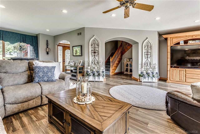 living area featuring arched walkways, stairway, and recessed lighting