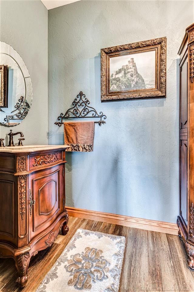 bathroom with a textured wall, baseboards, wood finished floors, and vanity