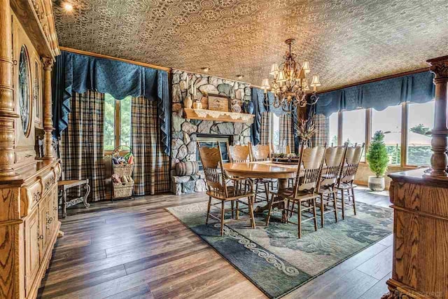 unfurnished dining area with an inviting chandelier, an ornate ceiling, a fireplace, and wood finished floors