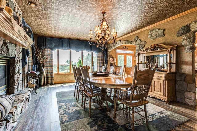 dining area with ornamental molding, an inviting chandelier, a textured ceiling, and hardwood / wood-style flooring