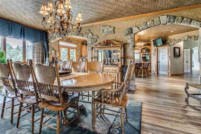 dining room featuring an ornate ceiling, arched walkways, crown molding, an inviting chandelier, and wood finished floors