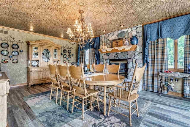 dining space featuring an ornate ceiling, dark wood-style floors, a fireplace, an inviting chandelier, and ornamental molding