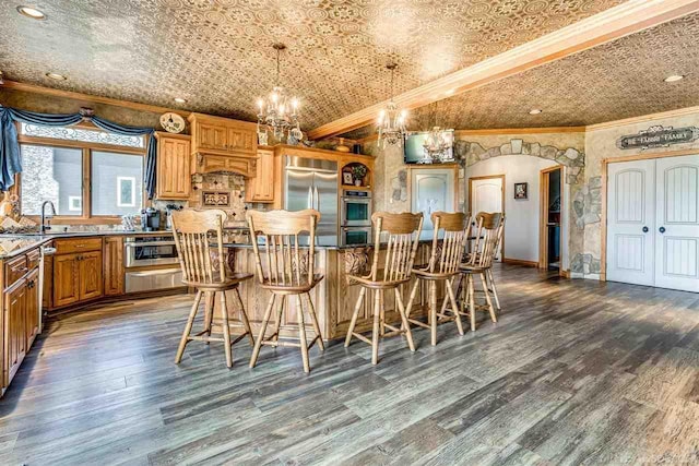 kitchen featuring arched walkways, an ornate ceiling, appliances with stainless steel finishes, a breakfast bar, and hanging light fixtures