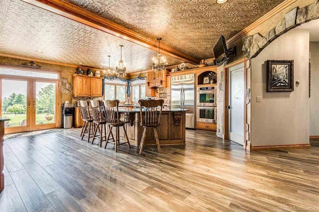 kitchen featuring an ornate ceiling, appliances with stainless steel finishes, crown molding, and decorative light fixtures