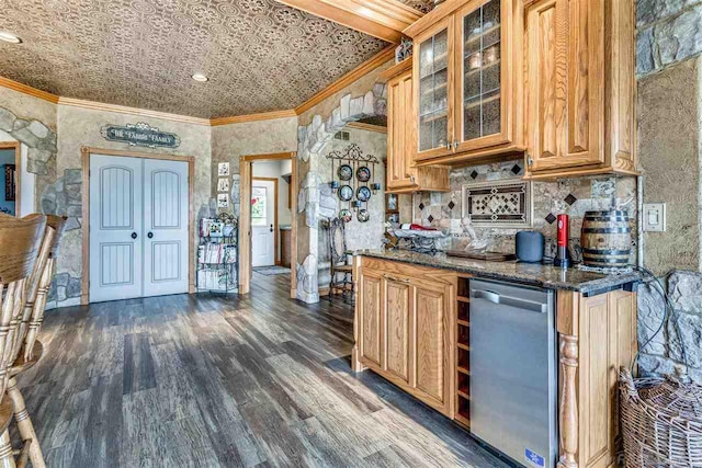 kitchen featuring backsplash, stainless steel dishwasher, dark stone countertops, dark wood-type flooring, and ornamental molding