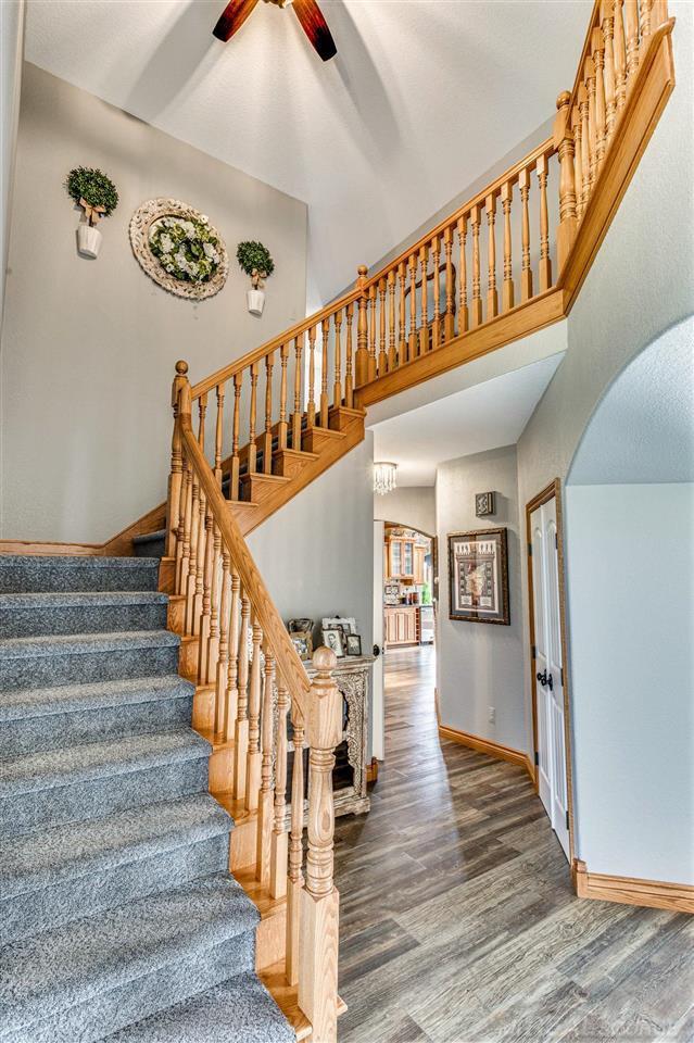 stairs with hardwood / wood-style flooring, ceiling fan, and a towering ceiling