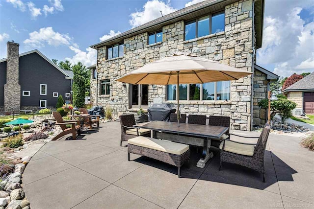 rear view of house with stone siding, a patio, and outdoor dining area