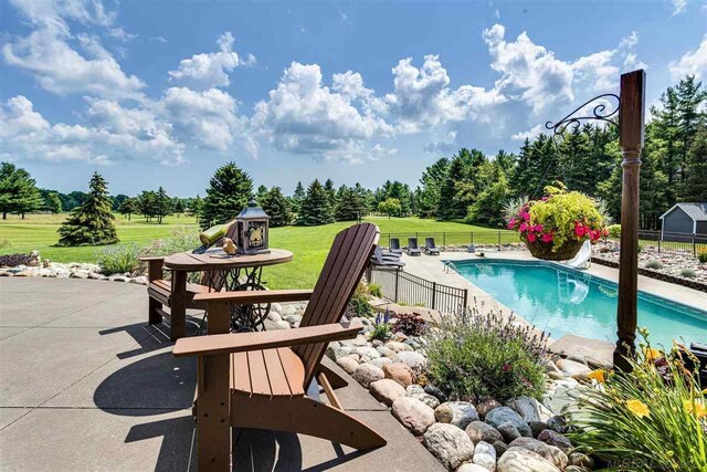 view of pool with a water slide, a yard, and a patio area