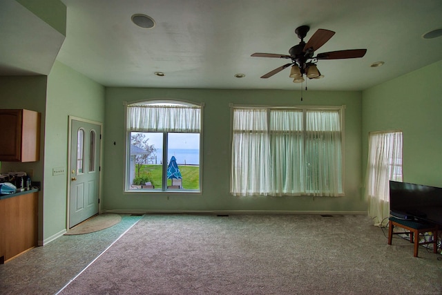 interior space featuring light colored carpet and ceiling fan