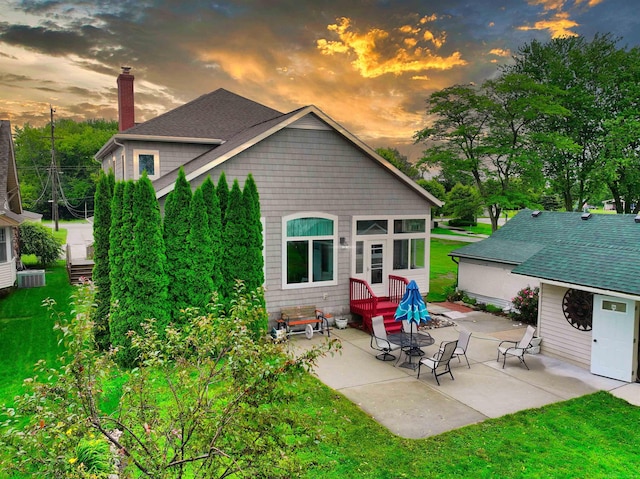 back house at dusk with a yard and a patio area